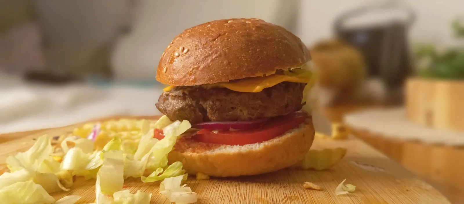 Close-up of a cheeseburger with fresh toppings on a wooden board, showcasing culinary appeal.